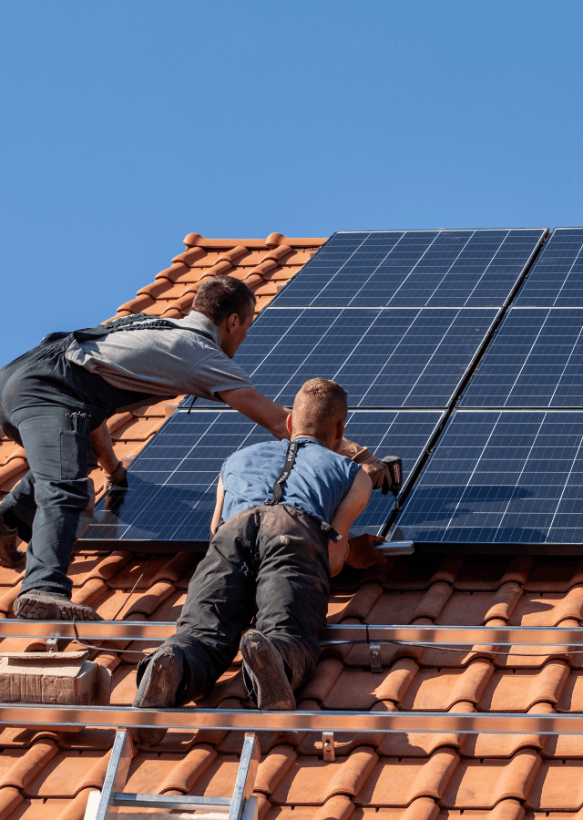 hommes en train d'installer des panneaux solaires sur le toit d'une maison